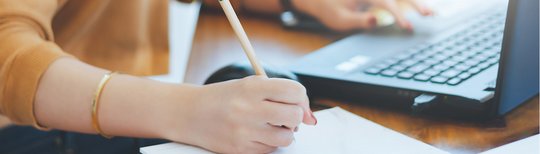 Eine Frau sitzt vor dem Computer und schreibt auf einem Blatt Papier mit. Im Bild steht "Noch Plätze frei". 